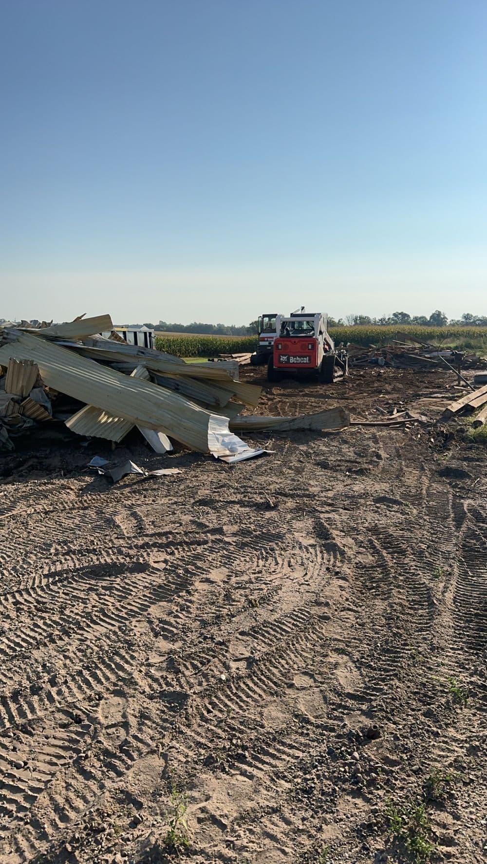 Construction site with heavy machinery and debris under a clear blue sky.
