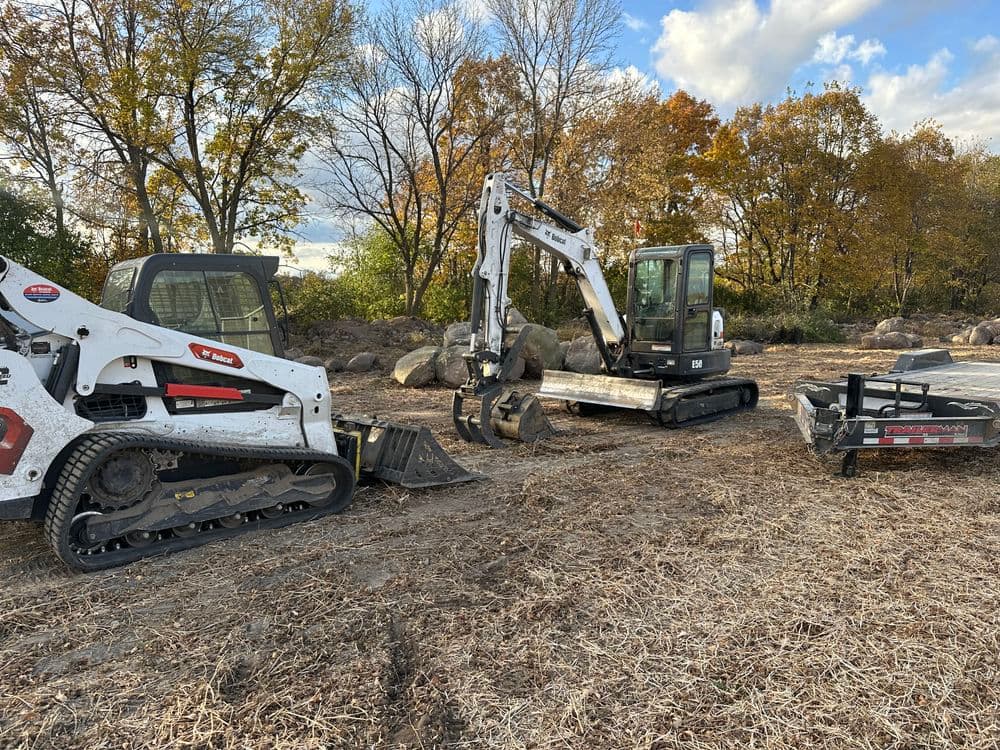 Excavation equipment on a construction site with autumn foliage in the background.